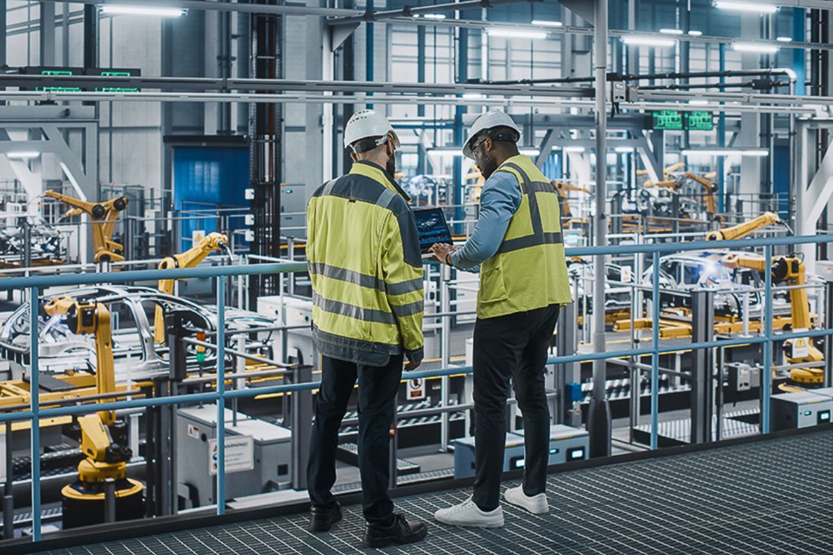 Workers wearing high-visibility jackets walking on factory floor