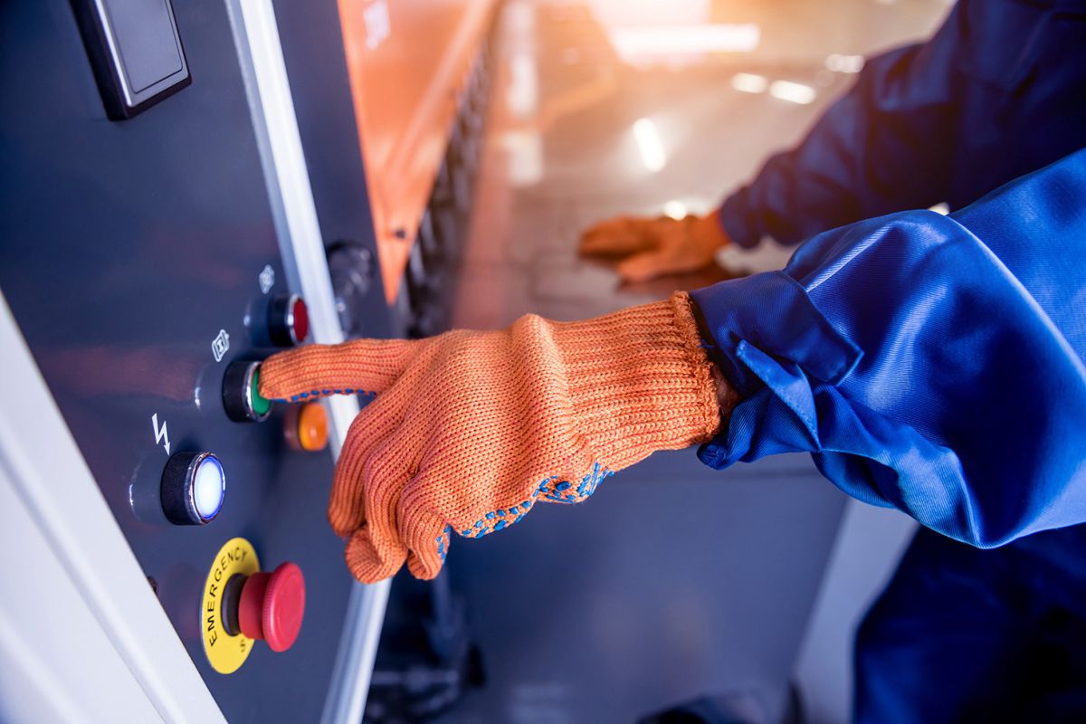 Gloved worker operating a safety control panel